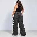 Modelo curvilínea con jeans negros tachonados.webp